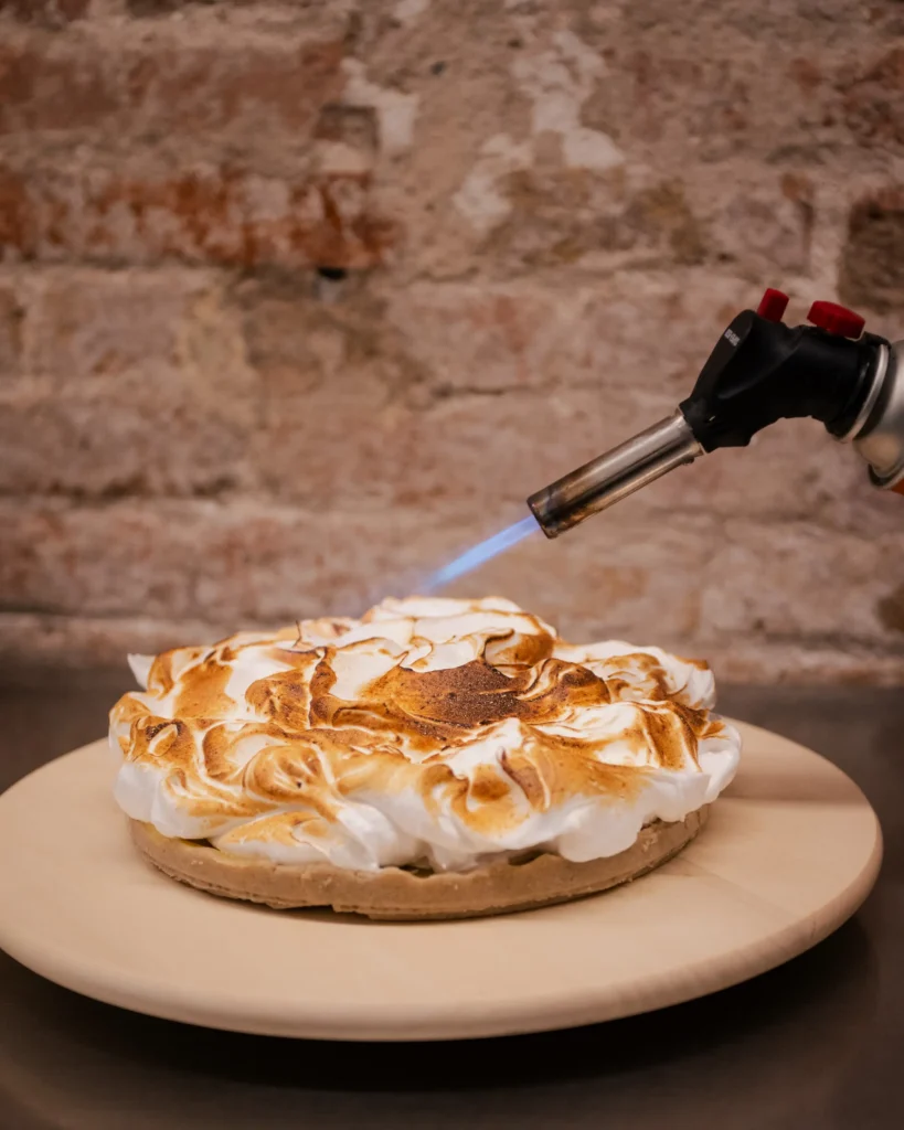 Gratinando a soplete un merengue sobre una tarta sin gluten